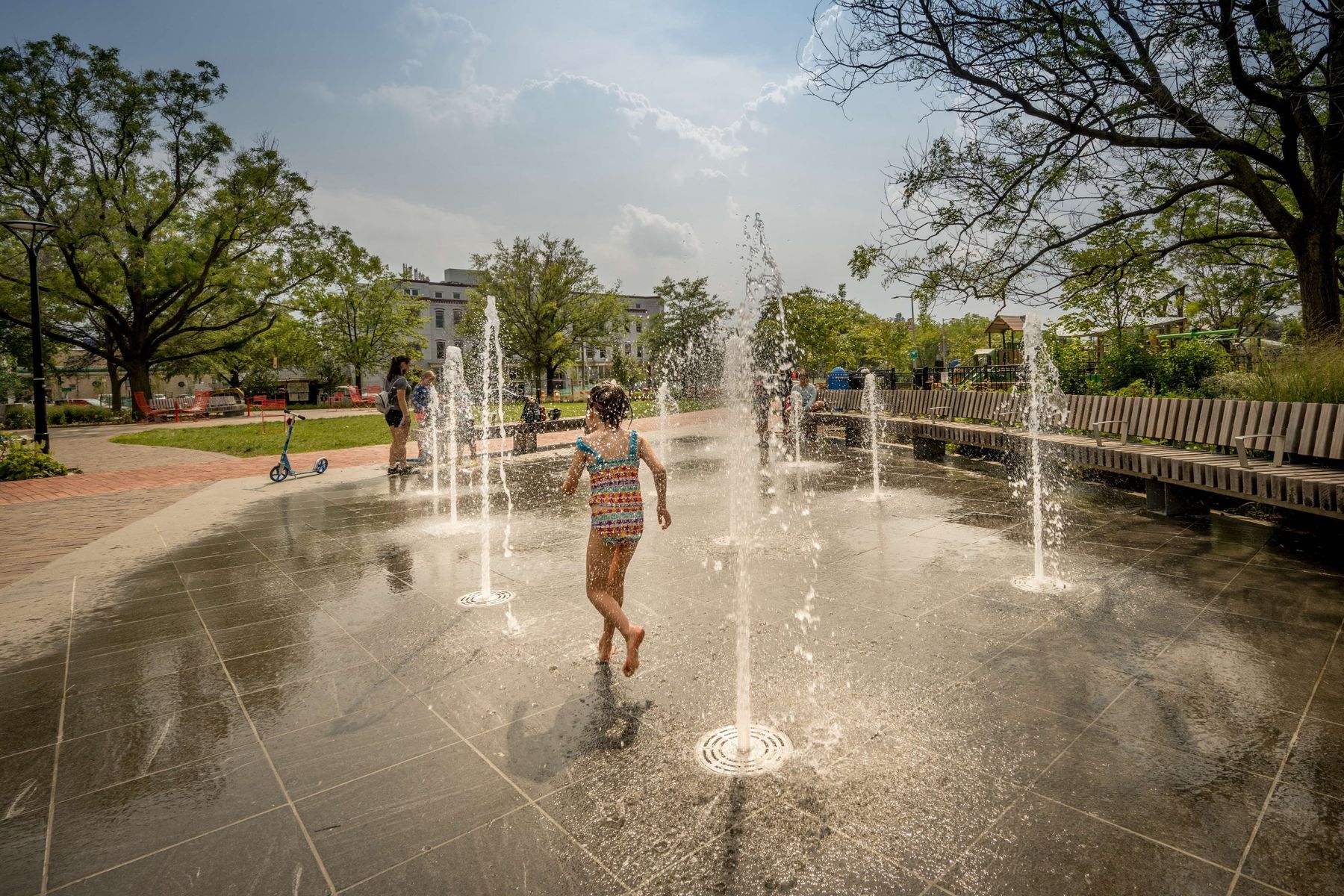 A child running through the spray fountains at Eastern Market Metro Park
